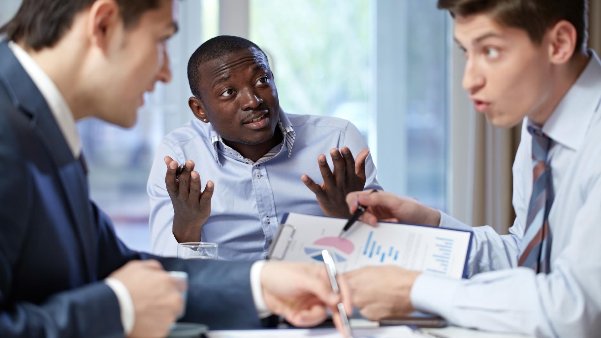 Três homens em ambiente de trabalho tendo uma discussão